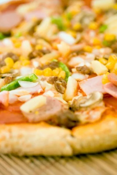 Пицца с ананасами, колбасой, сладкой кукурузой и томатами