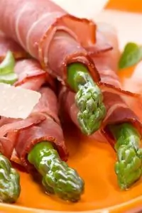 Спаржа, завернутая в ветчину серрано, с листьями салата, миндалем и виноградом