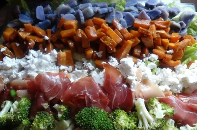 Слоеный овощной салат с прошутто и фетой на доске